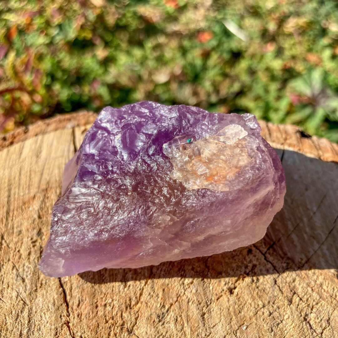 An amethyst crystal sitting on a piece of wood in color