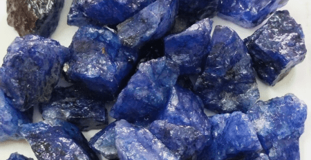 A pile of blue gemstones on a white surface.