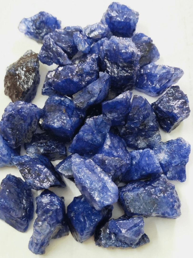 A pile of blue gemstones on a white surface.