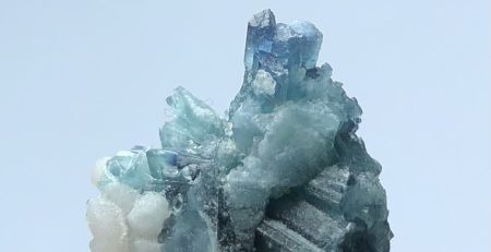 A blue and white crystal sitting on top of a piece of rock.