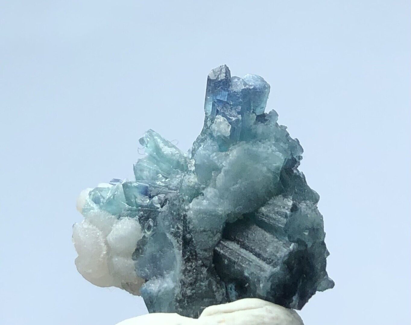 A blue and white crystal sitting on top of a piece of rock.