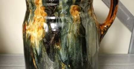 A black and brown jug sitting on a table.