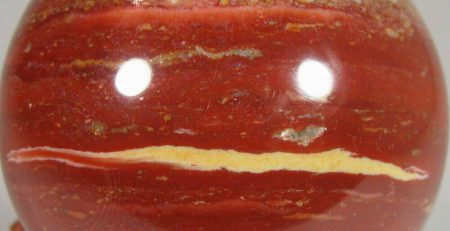 A red jasper sphere on a wooden stand.