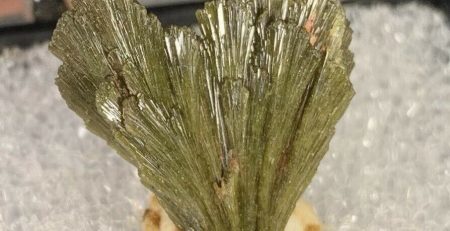 A piece of green mineral sitting on top of a piece of ice.