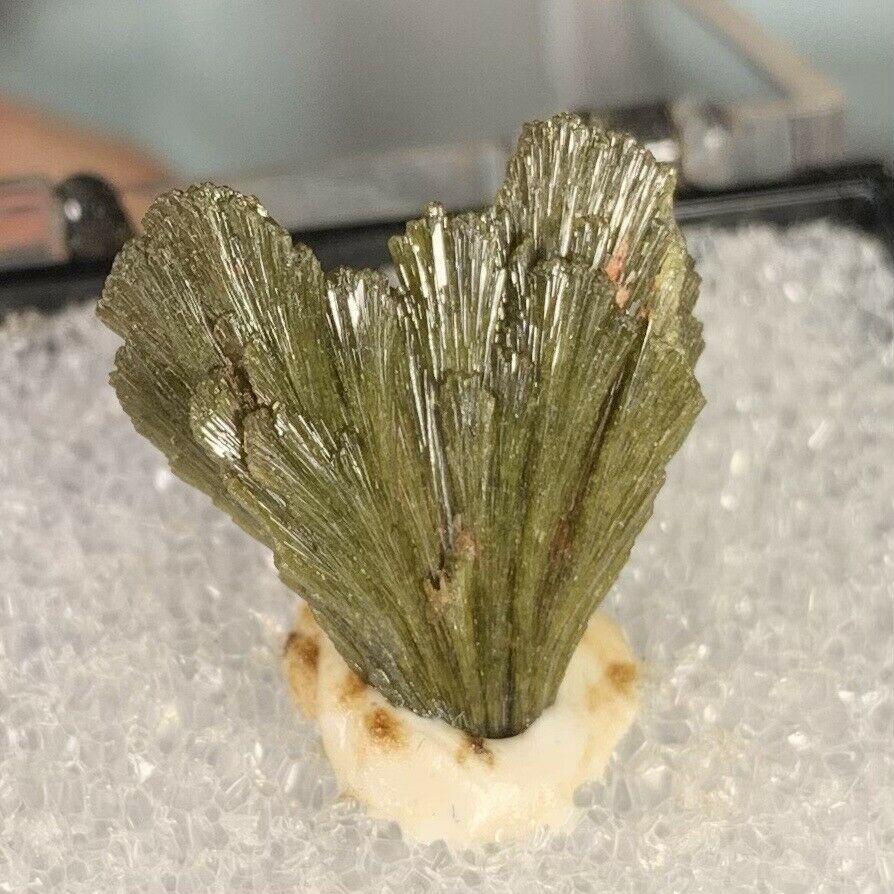 A piece of green mineral sitting on top of a piece of ice.