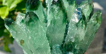 A person holding a green crystal in their hand.