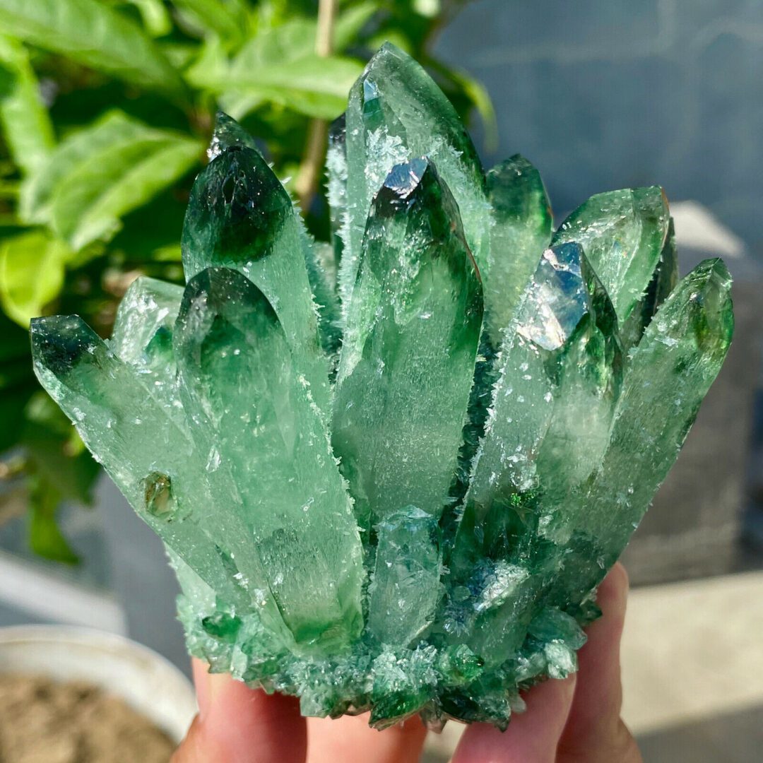 A person holding a green crystal in their hand.