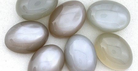 A group of grey and white oval shaped beads on a white surface.