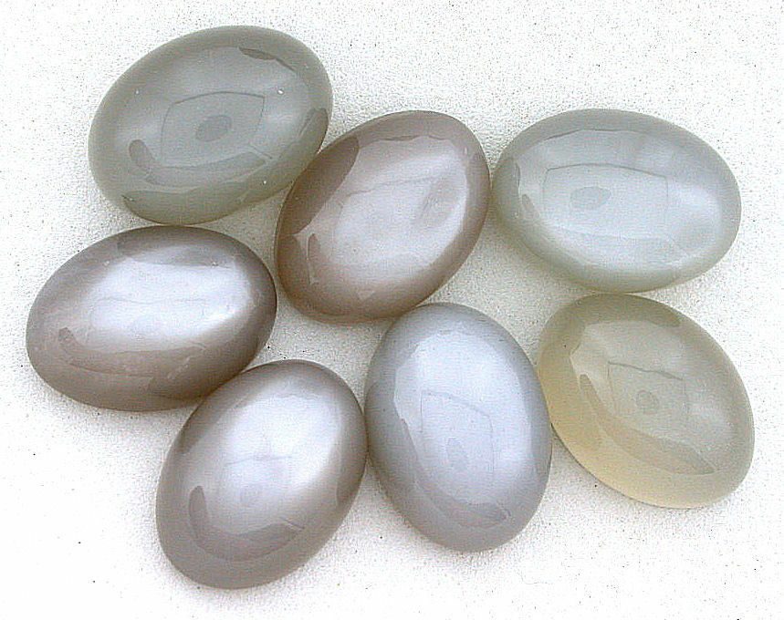 A group of grey and white oval shaped beads on a white surface.