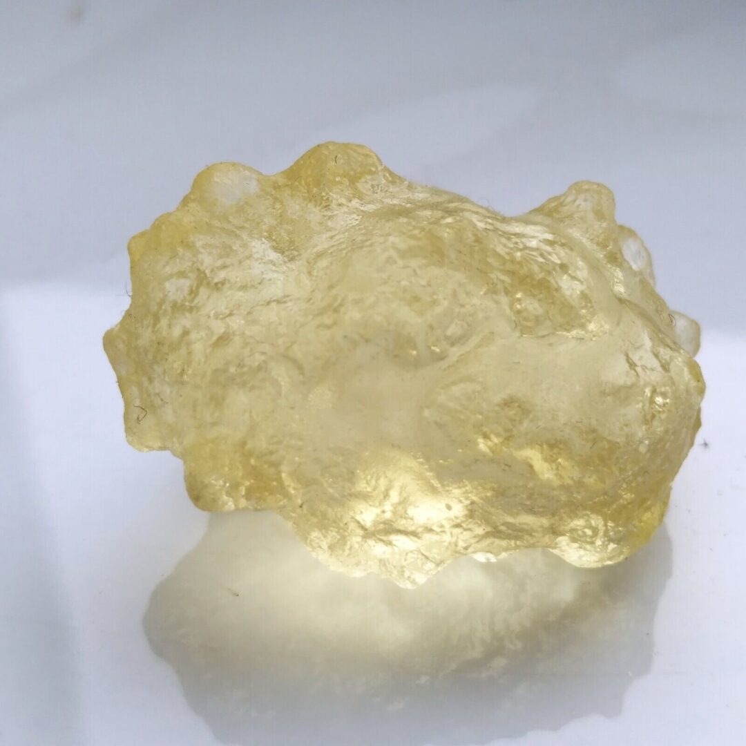 A piece of yellow quartz on a white surface.