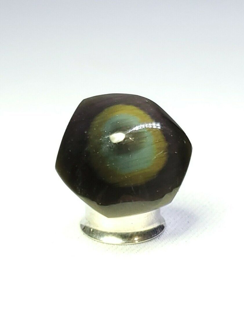 A black and green eye on a silver base.