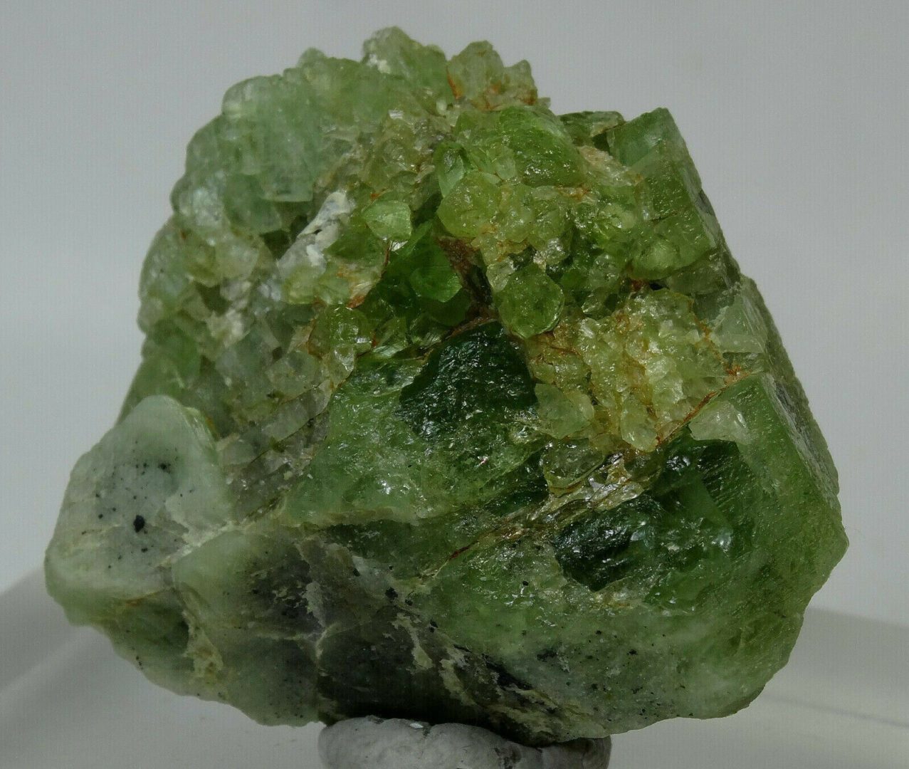 A piece of green quartz sitting on top of a piece of glass.