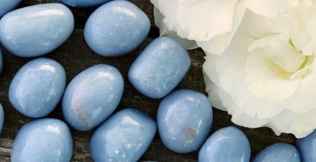 Blue jade pebbles on a wooden table with a flower in color.