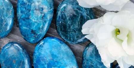 A group of blue stones and flowers on a wooden surface.