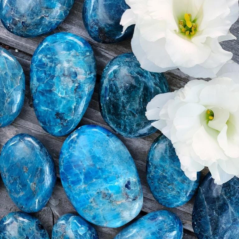 A group of blue stones and flowers on a wooden surface.