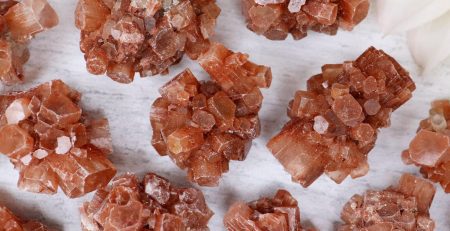 A bunch of red quartz crystals on a white surface.