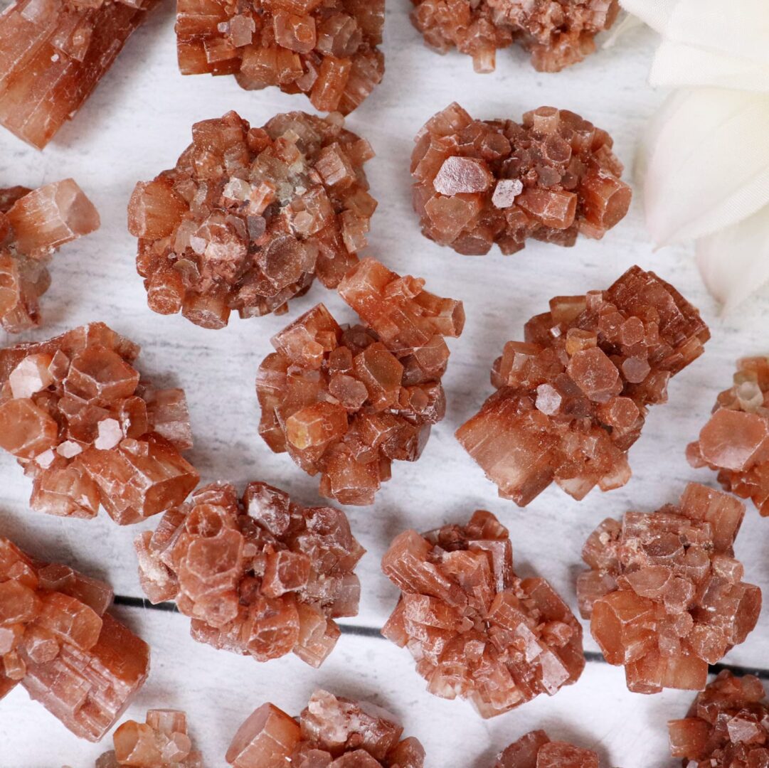 A bunch of red quartz crystals on a white surface.