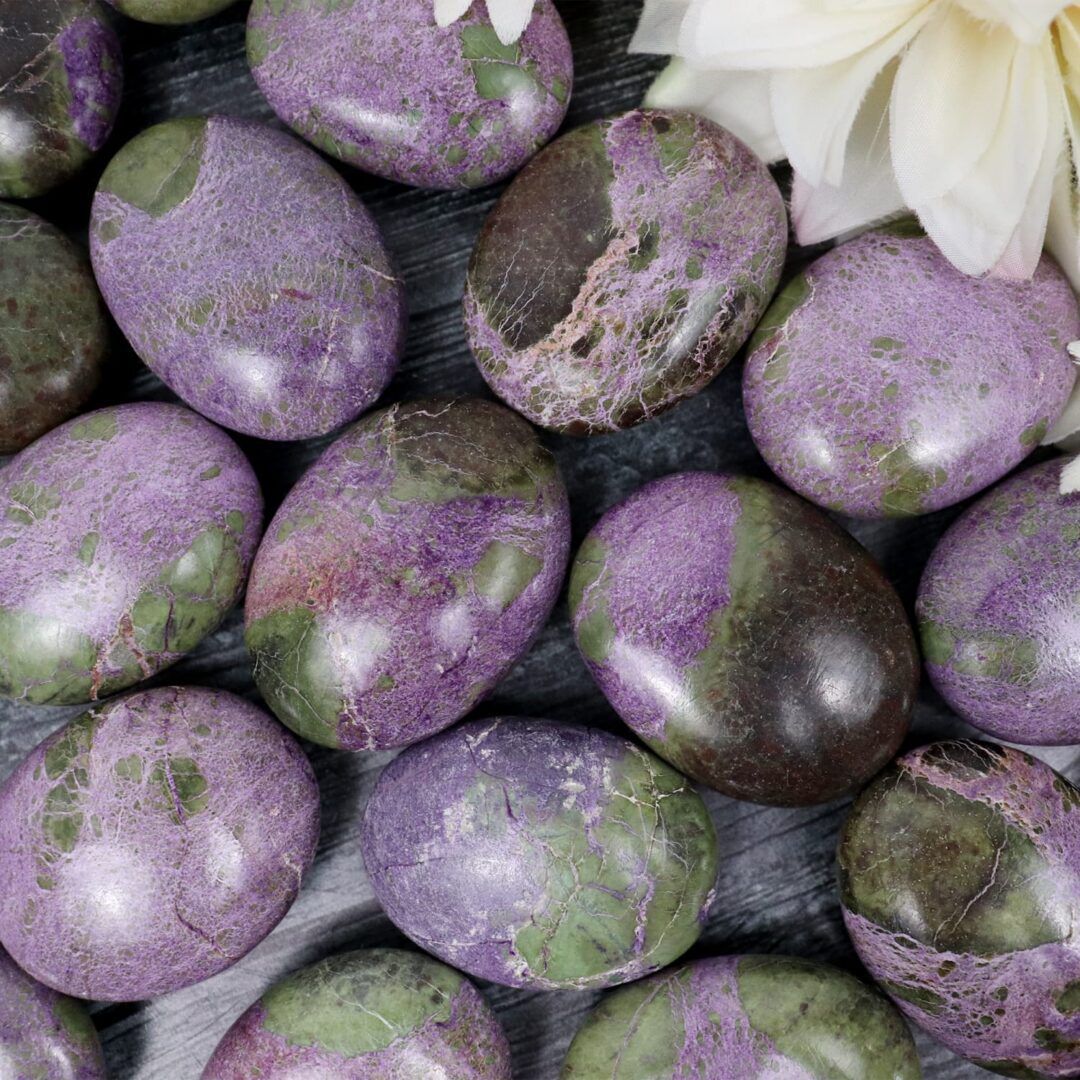 A bunch of purple and green marble eggs on a table.