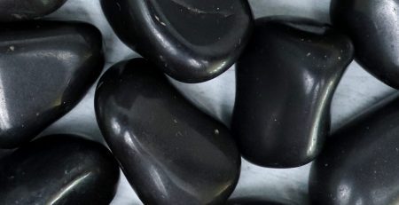 A pile of black pebbles on a white surface.