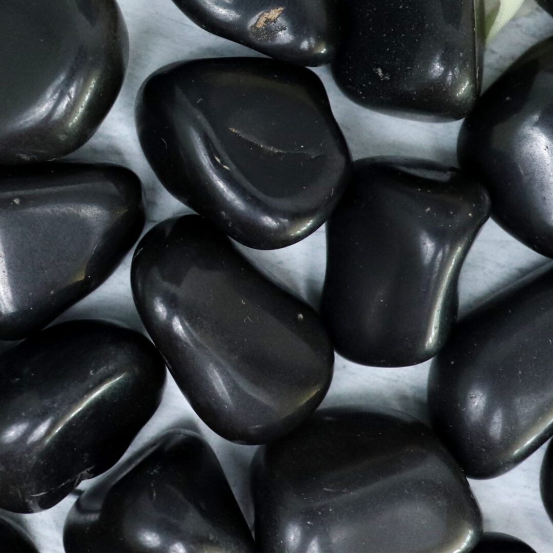 A pile of black pebbles on a white surface.