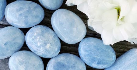 A bunch of blue stones and flowers on a wooden table.