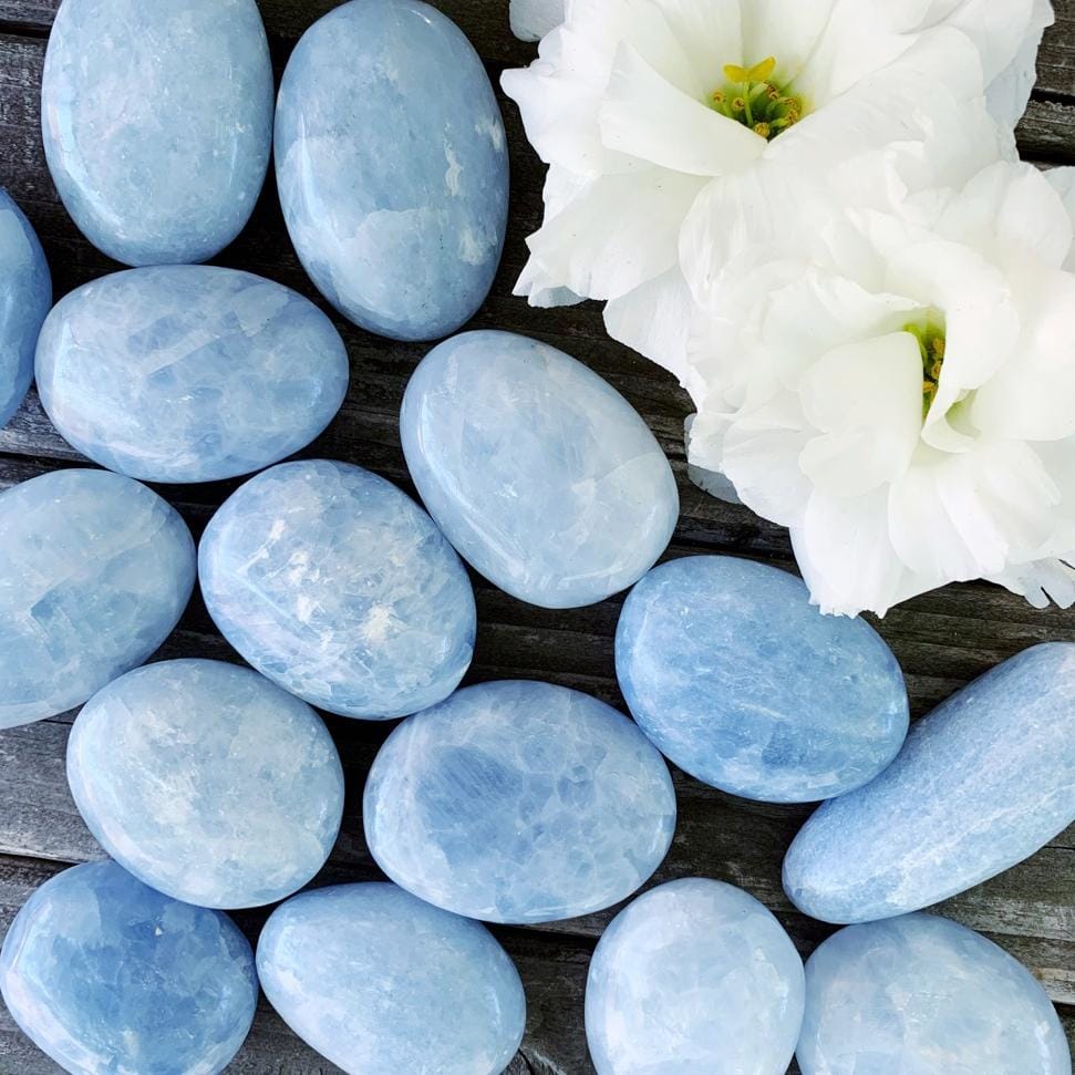 A bunch of blue stones and flowers on a wooden table.