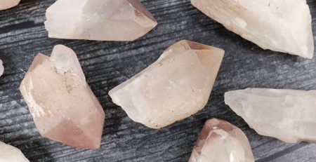 A bunch of pink quartz crystals on a wooden surface.