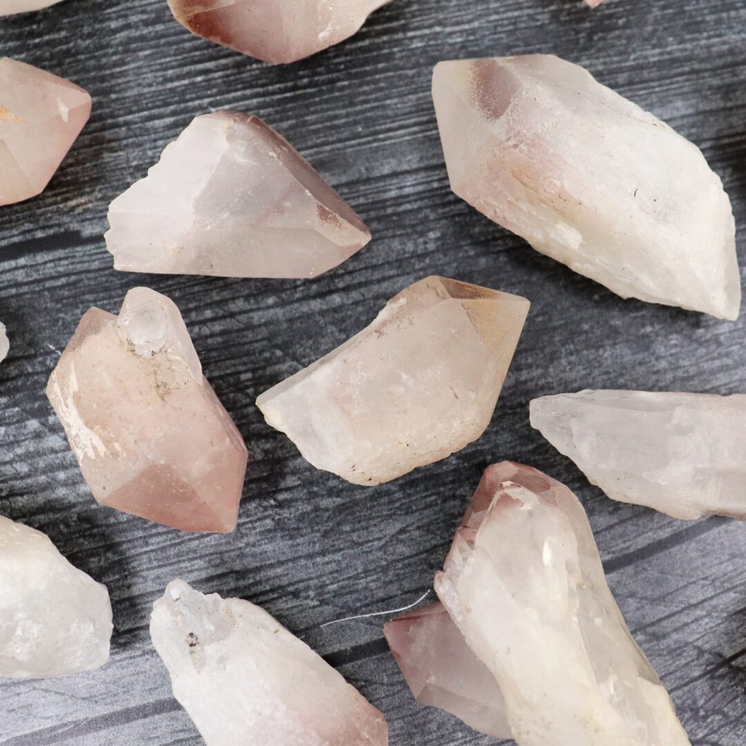 A bunch of pink quartz crystals on a wooden surface.