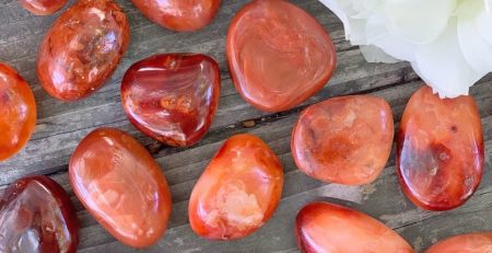 A group of red and orange stones on a wooden table.