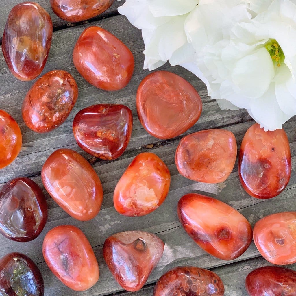 A group of red and orange stones on a wooden table.