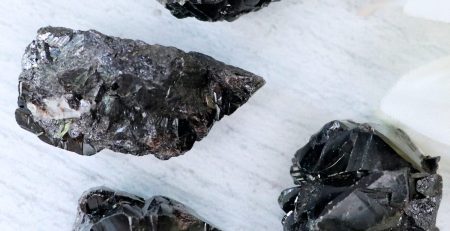 A group of black quartz crystals on a white surface.