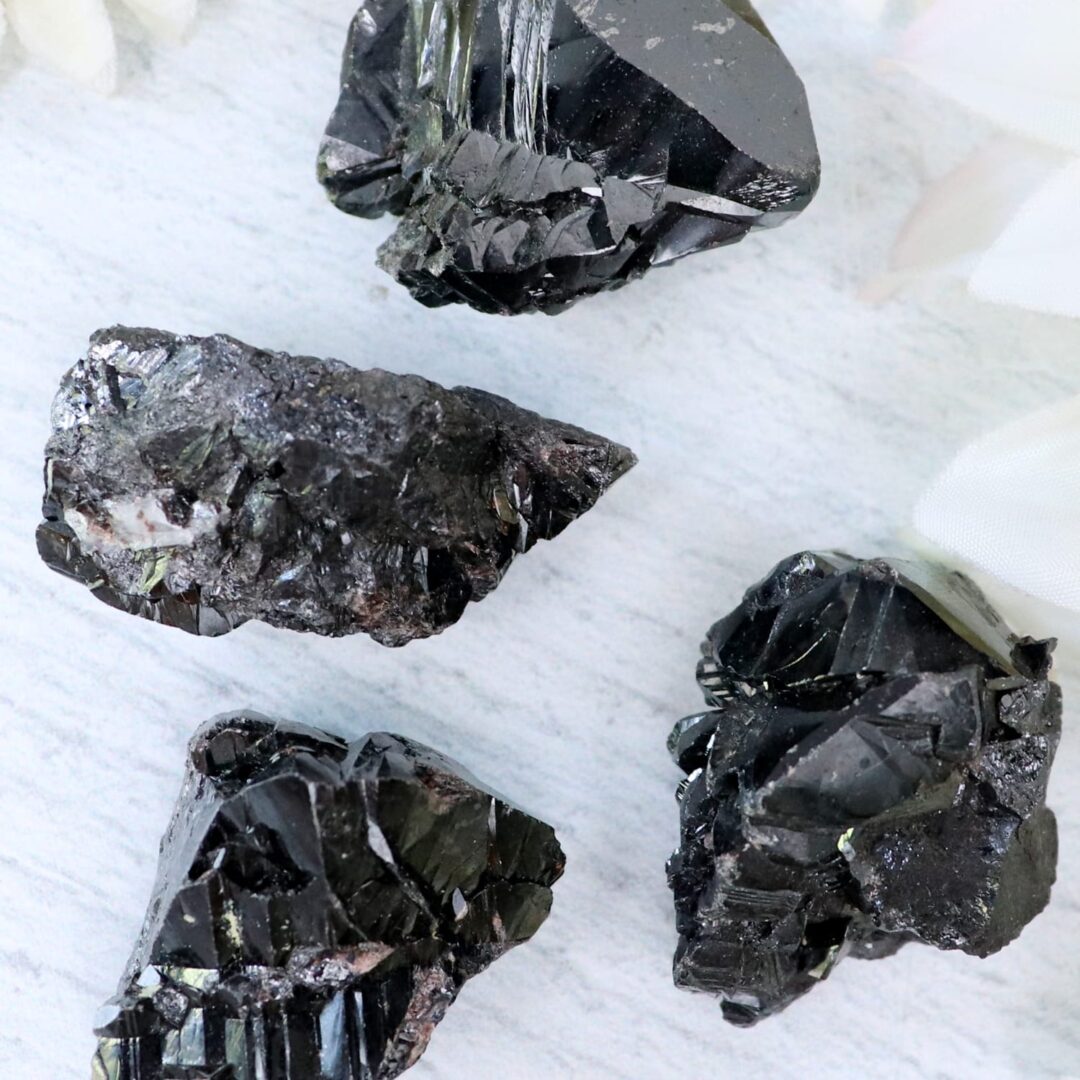 A group of black quartz crystals on a white surface.