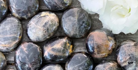 A bunch of black and white stones on a wooden table.