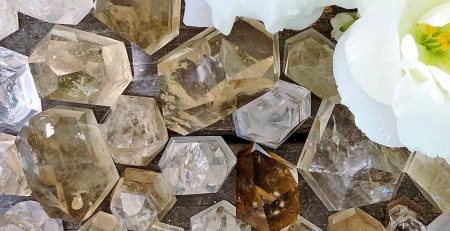 A bunch of crystals and a white flower on a wooden surface.