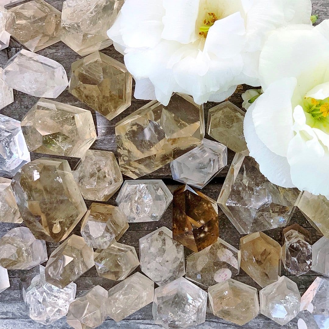 A bunch of crystals and a white flower on a wooden surface.