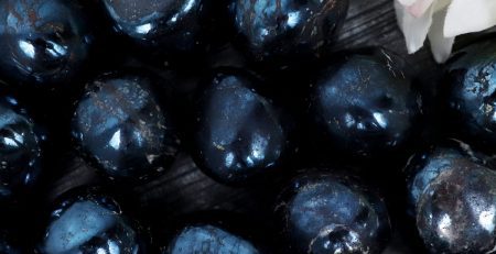 A bunch of black pearls on a wooden table.