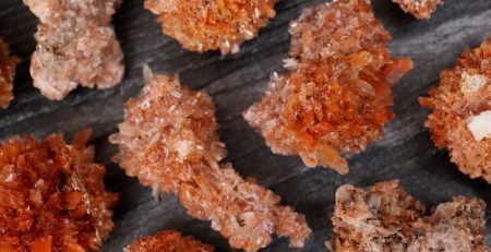 A bunch of orange crystals on a wooden surface.