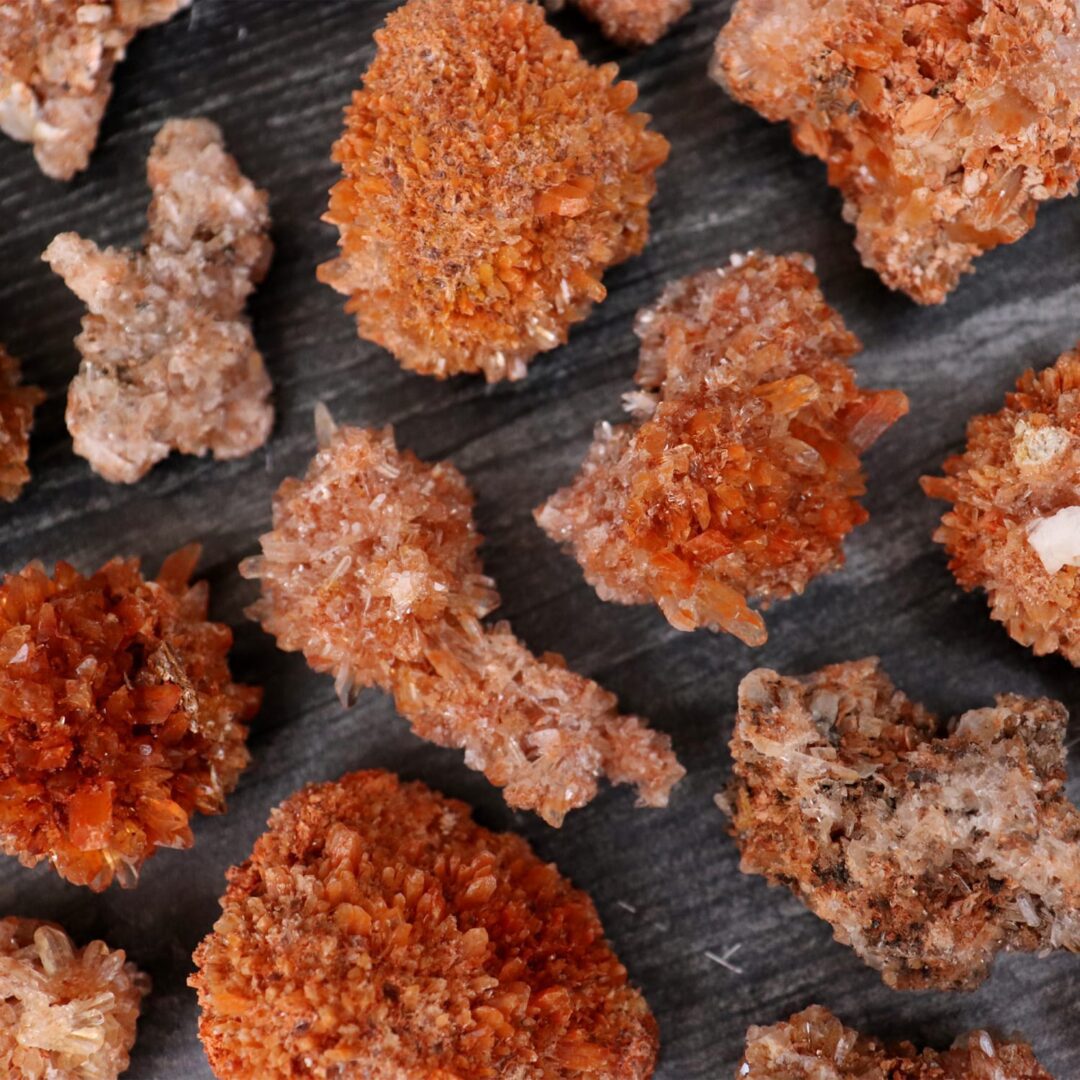 A bunch of orange crystals on a wooden surface.