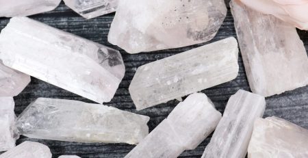 A pile of pink rose quartz crystals on a wooden table.