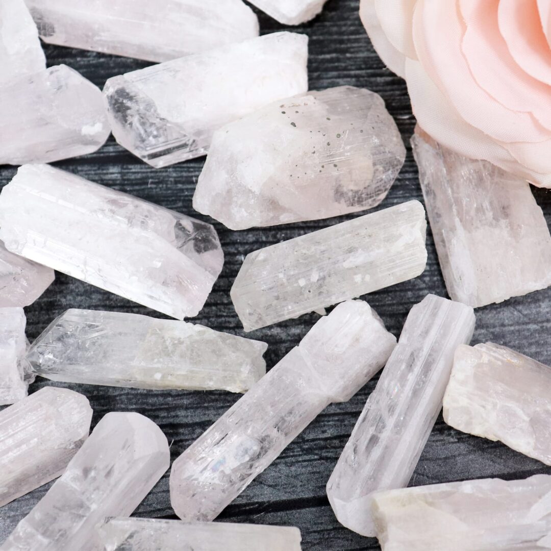 A pile of pink rose quartz crystals on a wooden table.