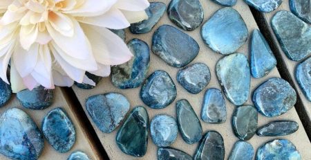 Blue labradorite pebbles on a wooden table with a flower.