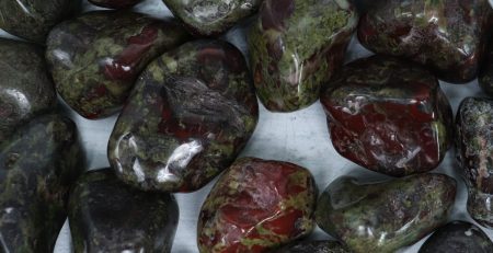 A pile of red and green stones on a wooden table.