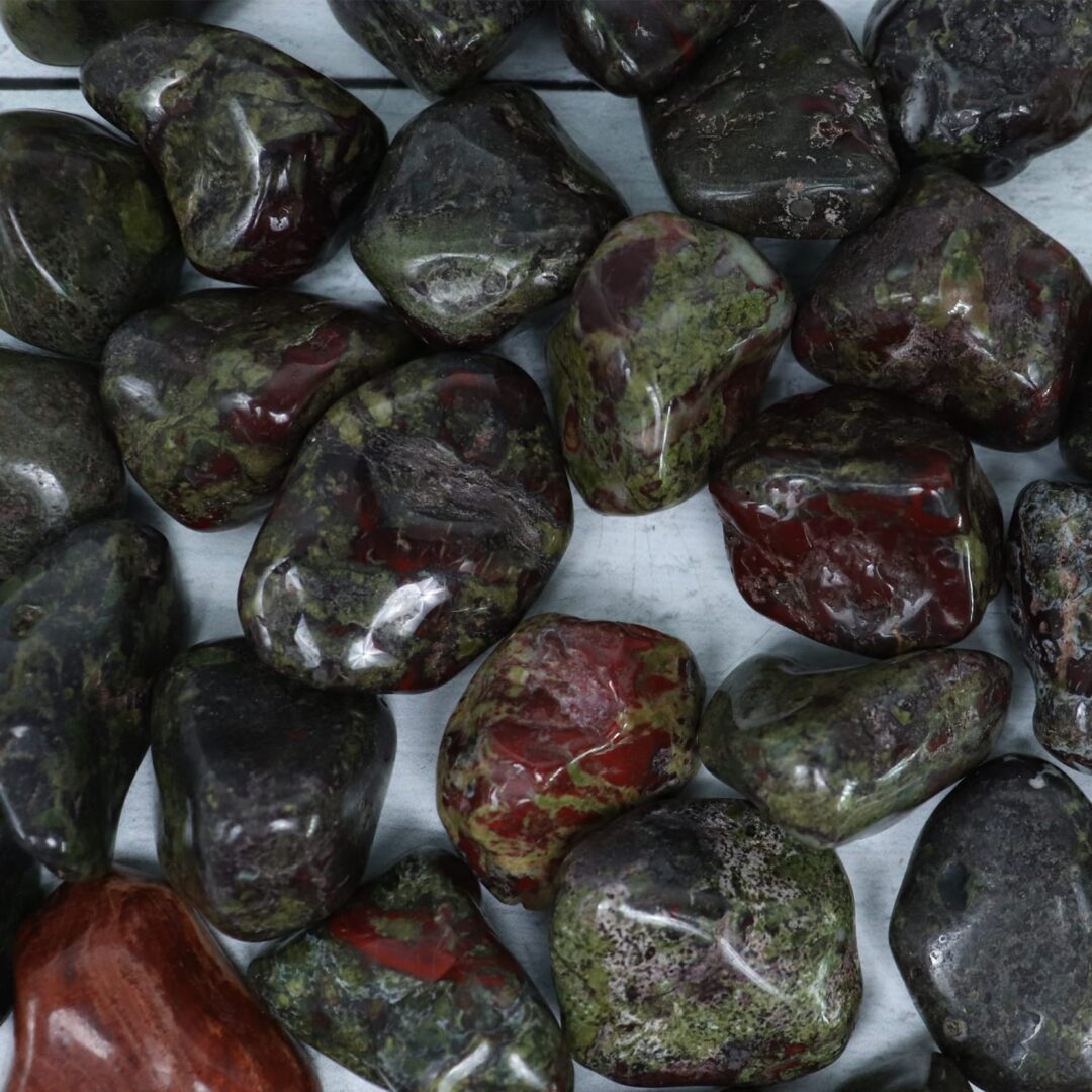 A pile of red and green stones on a wooden table.