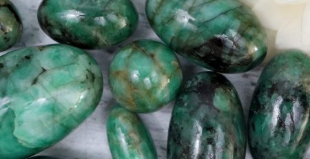 Green emerald stones on a white surface.