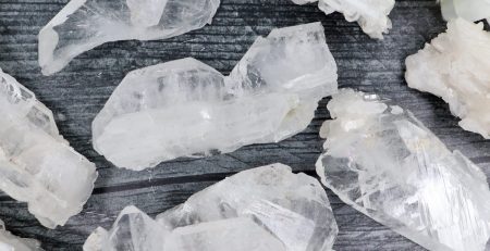 A bunch of white quartz crystals on a wooden table.