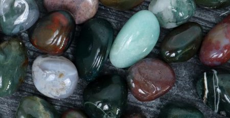 A pile of green and red stones on a wooden surface.