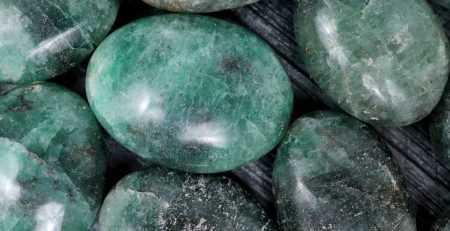 Green emerald stones on a wooden surface.