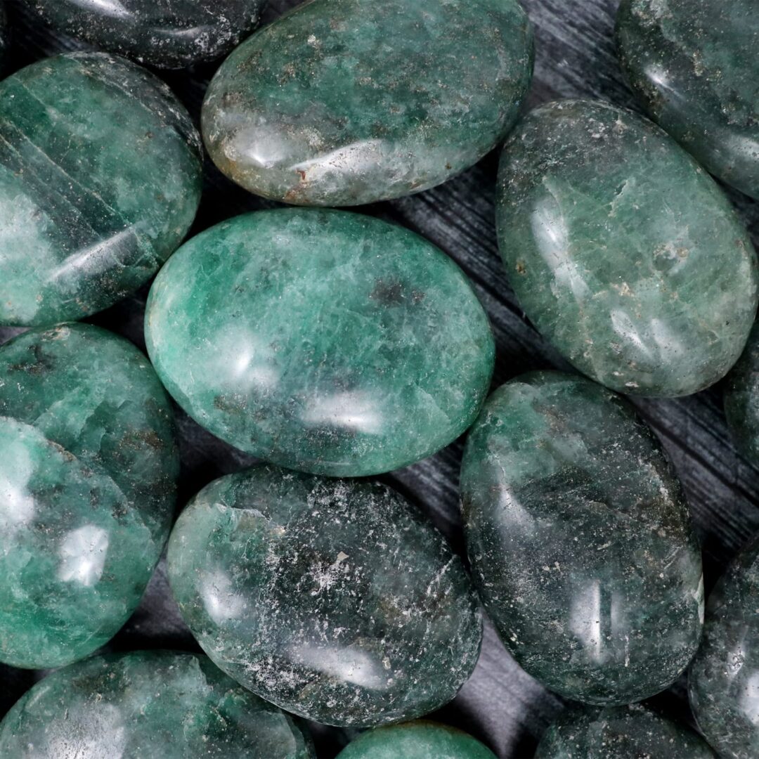 Green emerald stones on a wooden surface.