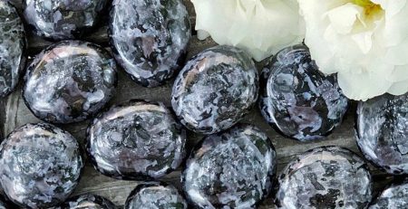 A bunch of black and white marble eggs on a wooden table.