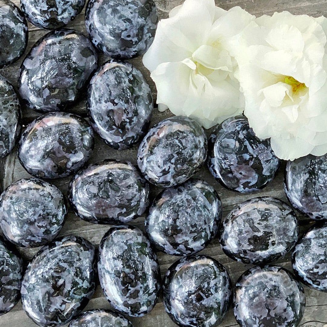 A bunch of black and white marble eggs on a wooden table.